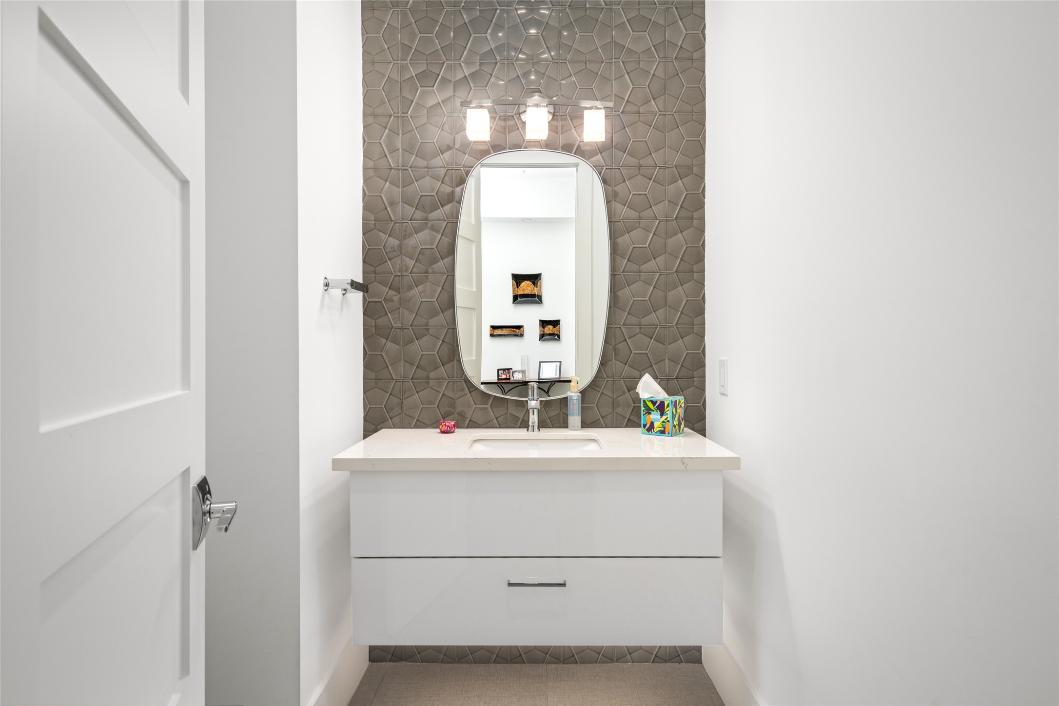 5706 Birdwood Road Houston, TX 77096 - Photo 9 of 50 The full accent wall of polished, geometric tile behind the white floating vanity, sconce lighting and mirror create the perfect amount of understated drama in this half bath/powder room.