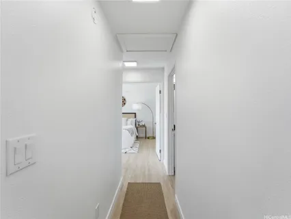 a view of a hallway with wooden floor and a bathroom