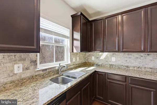 a kitchen with granite countertop a sink and a wooden cabinets