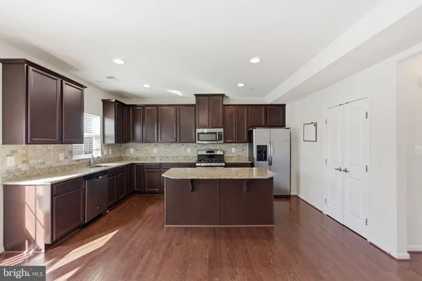 a large kitchen with stainless steel appliances kitchen island granite countertop a stove and a sink