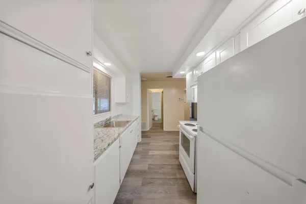 a hallway with white cabinets and sink