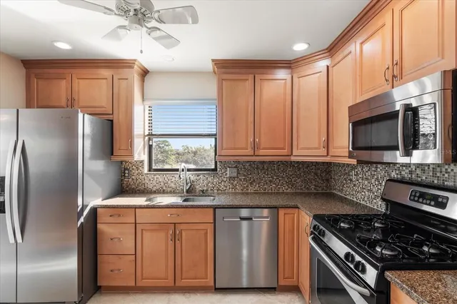 a kitchen with stainless steel appliances granite countertop a stove a sink dishwasher a refrigerator and a microwave