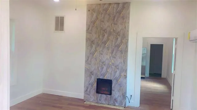 a view of an empty room with wooden floor and a fireplace
