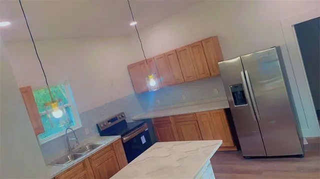 a kitchen with stainless steel appliances wooden cabinets a refrigerator and a wooden floor