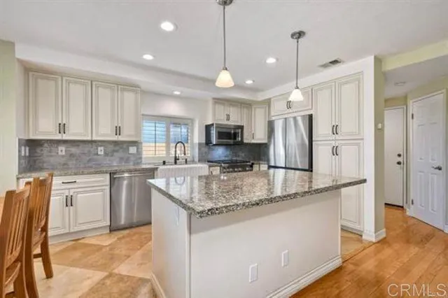 a kitchen with stainless steel appliances granite countertop a sink refrigerator and cabinets