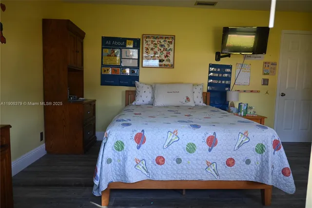 a bedroom with a bed and flat tv screen on dresser