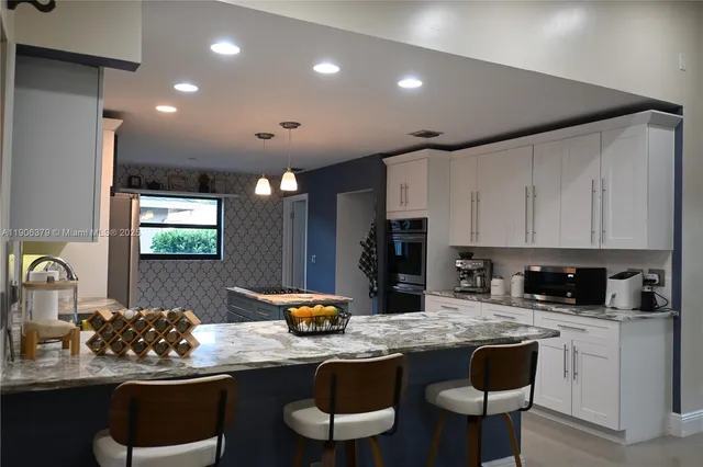 a kitchen with granite countertop a sink and white cabinets