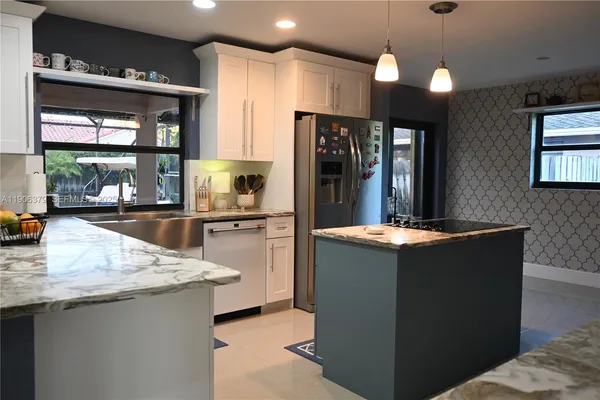 a kitchen with stainless steel appliances granite countertop a refrigerator a sink and a stove
