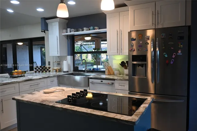 a kitchen with stainless steel appliances granite countertop a refrigerator a sink and a stove