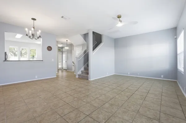 an empty room with a chandelier fan and windows
