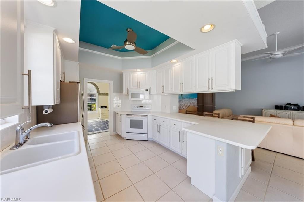 3060 Ellice Way Naples, FL 34119 - Photo 10 of 31 Kitchen featuring a raised ceiling, a ceiling fan, white cabinetry, a peninsula, and white appliances