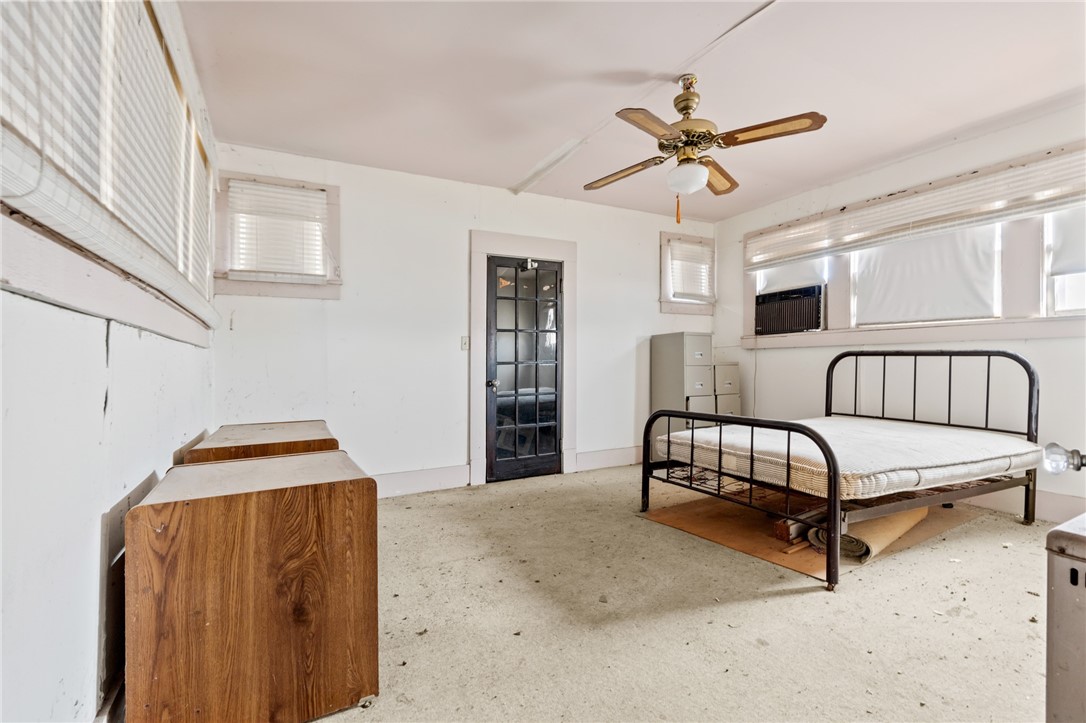 306 East Adams Street Itasca, TX 76055 - Photo 21 of 29 a bedroom with a bed and a chandelier