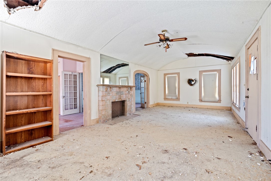 306 East Adams Street Itasca, TX 76055 - Photo 3 of 29 a view of a livingroom with a fireplace a ceiling fan and windows