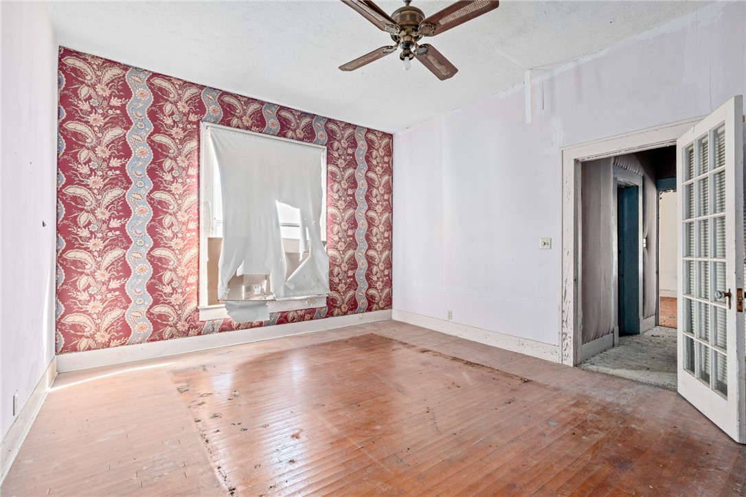 306 East Adams Street Itasca, TX 76055 - Photo 6 of 29 a view of a livingroom with wooden floor and a ceiling fan