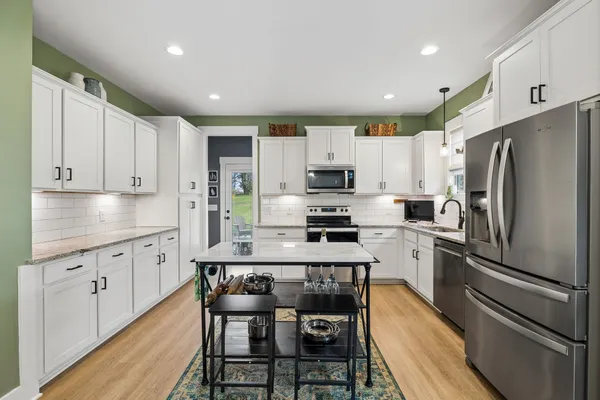 a kitchen with kitchen island granite countertop white cabinets and stainless steel appliances