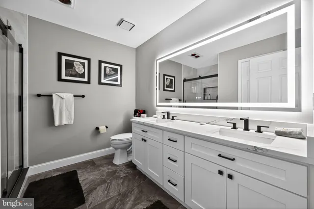 a bathroom with a granite countertop toilet sink and mirror