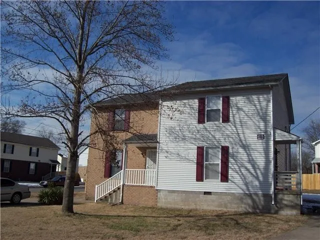 a front view of a house with large tree