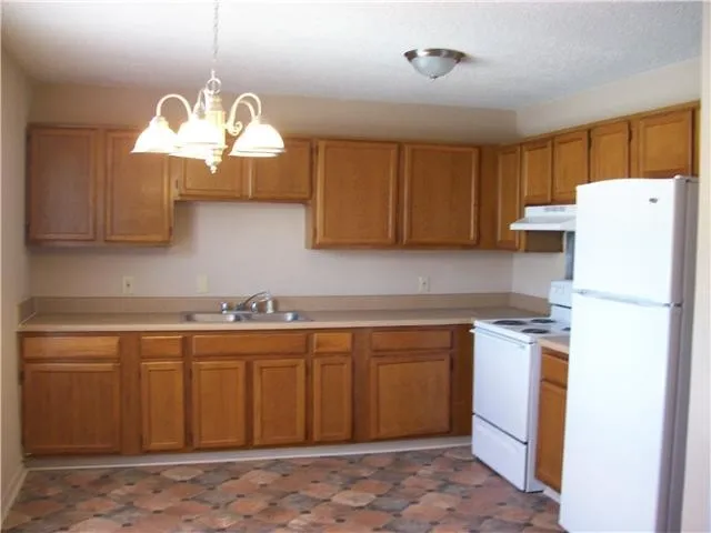 a kitchen with a cabinets a chandelier and stainless steel appliances
