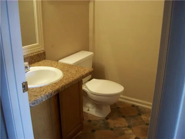 a bathroom with a granite countertop toilet and a sink