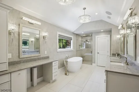 a spacious bathroom with a granite countertop sink a toilet a mirror and a bathtub