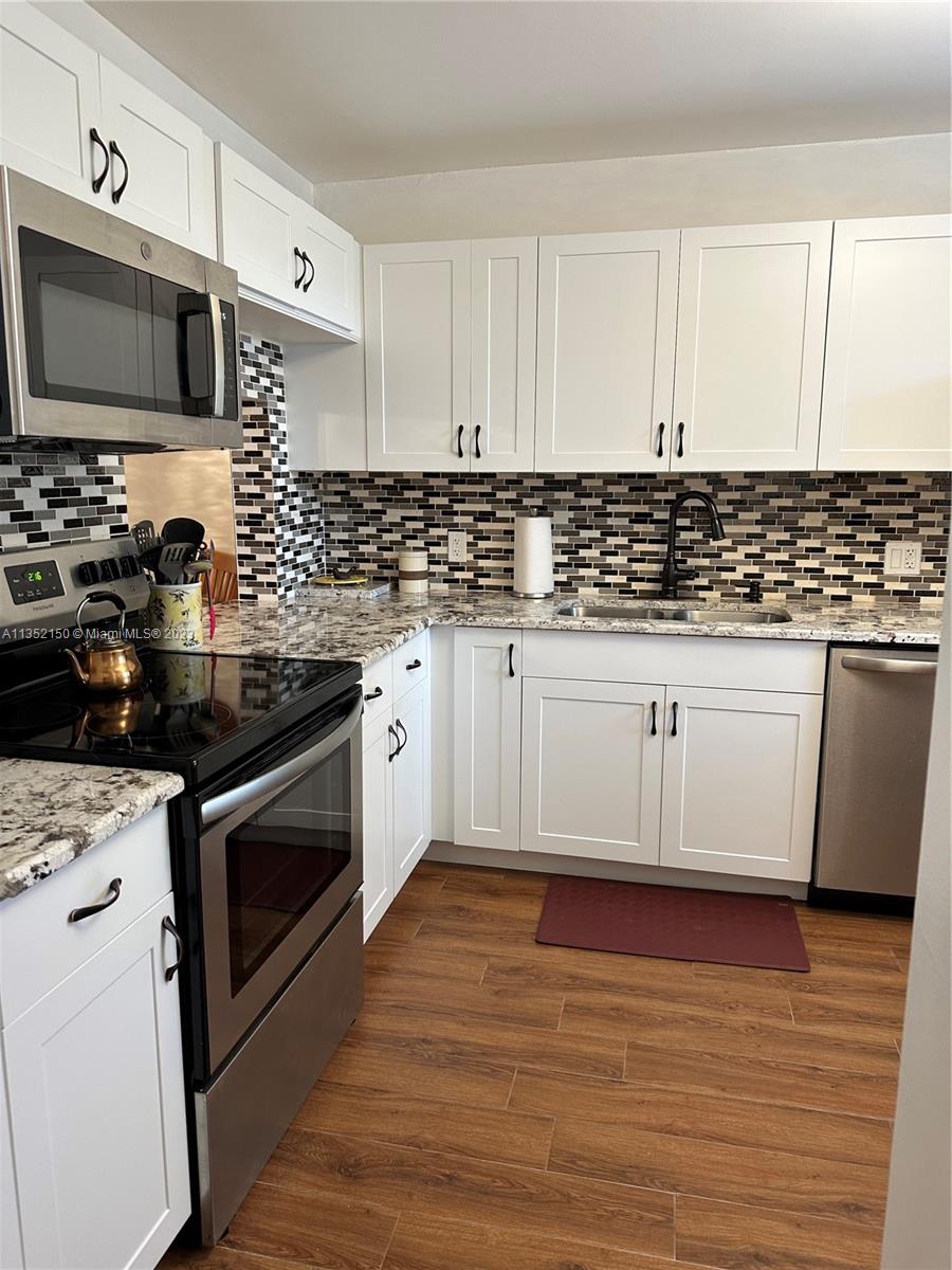 250 Gate Road, Unit 258 Hollywood, FL 33024 - Photo 9 of 30 a kitchen with granite countertop a sink and a stove top oven