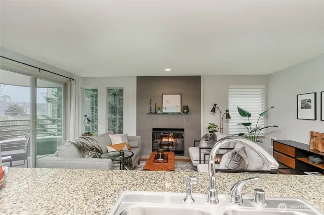 a living room with fireplace furniture large window and wooden floor
