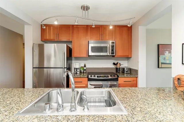 a kitchen with stainless steel appliances kitchen island granite countertop a refrigerator and a stove top oven
