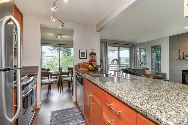 a kitchen with stainless steel appliances granite countertop sink stove dining table and chairs