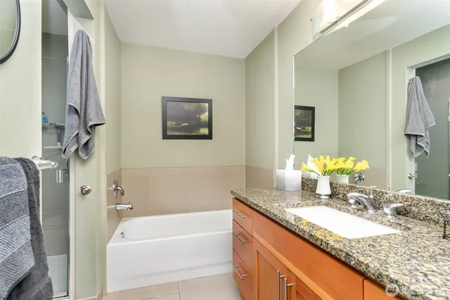 a bathroom with a granite countertop tub sink and mirror