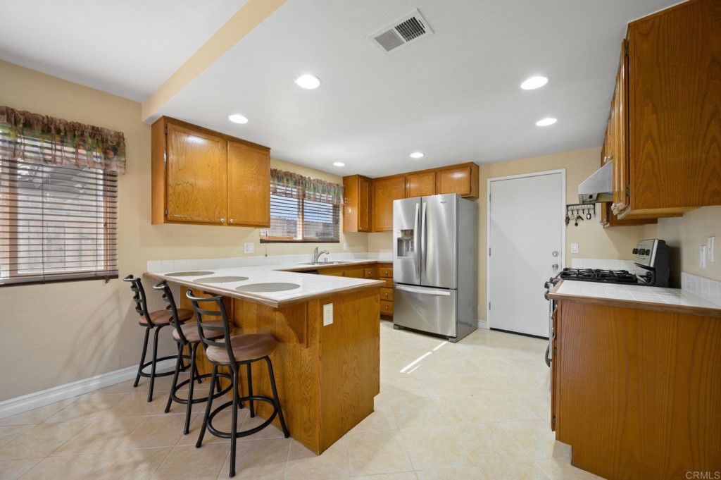 228 Ocotillo Place Oceanside, CA 92057 - Photo 12 of 31 a kitchen with stainless steel appliances granite countertop a table chairs sink refrigerator and microwave