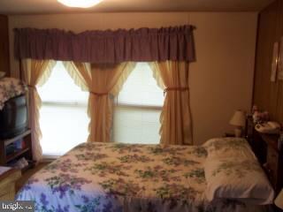 6525 Morris Road Pittsville, MD 21850 - Photo 8 of 8 a bedroom with a bed and a flat tv screen