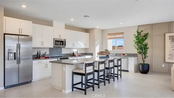 a kitchen with microwave a refrigerator and chairs