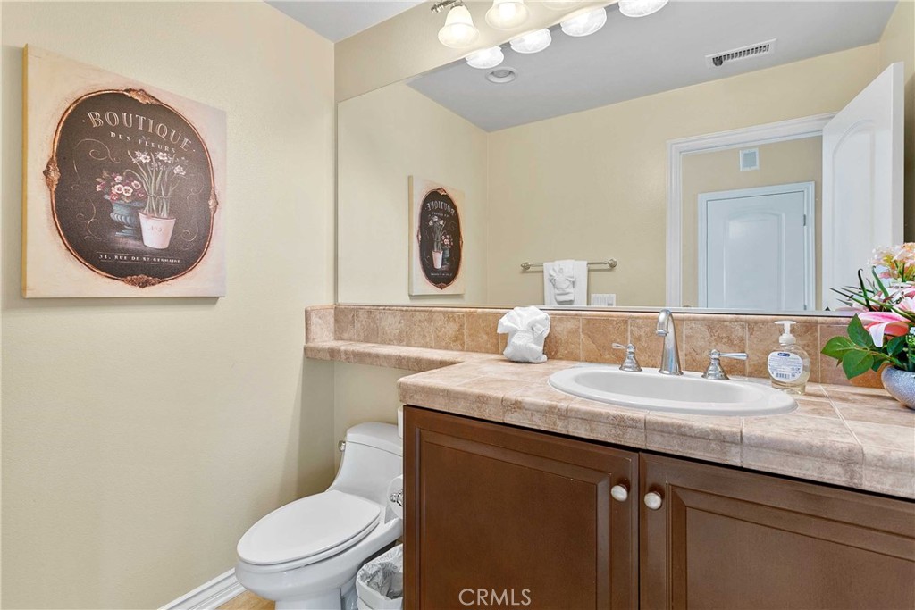 14496 Meadow Brook Eastvale, CA 92880 - Photo 21 of 33 a bathroom with a granite countertop toilet a sink and a mirror