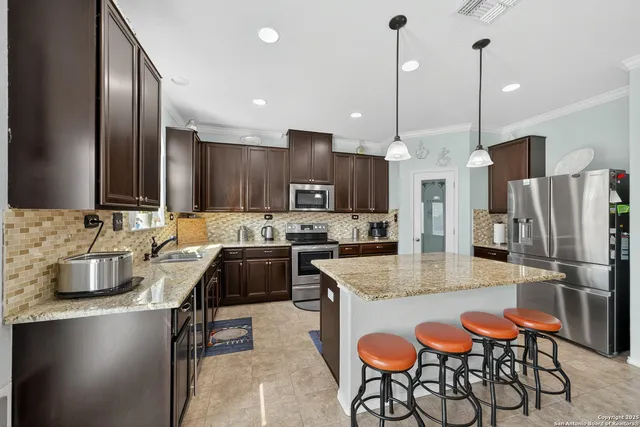 a kitchen with granite countertop a table chairs stove and refrigerator