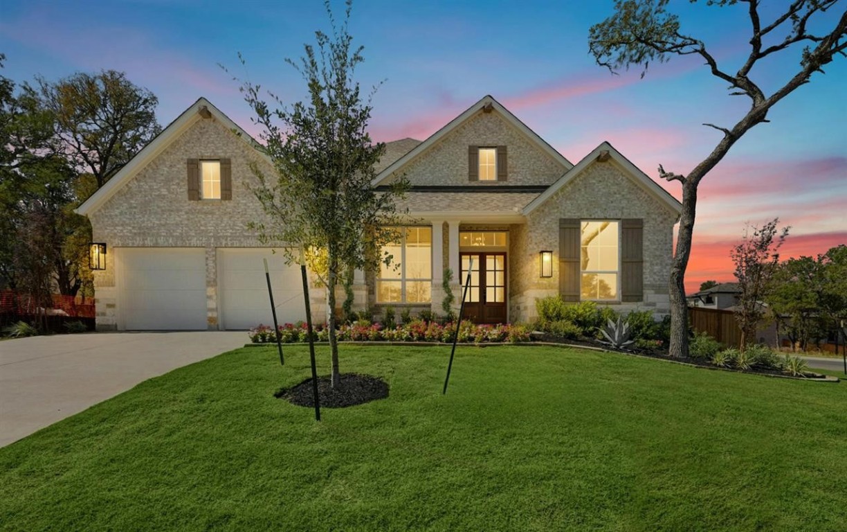 a front view of a house with a yard and tree
