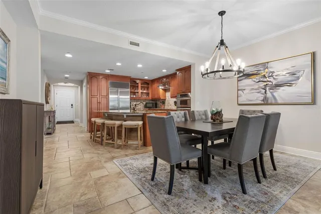 a view of a dining room and livingroom with furniture a chandelier and kitchen view