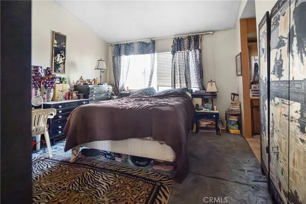 a bedroom with a bed table chair and a window