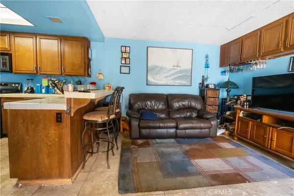 a living room with stainless steel appliances furniture a fireplace and a flat screen tv