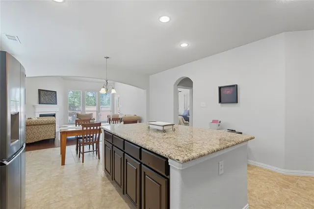 a large kitchen with stainless steel appliances granite countertop a refrigerator oven a sink a stove a dining table and chairs