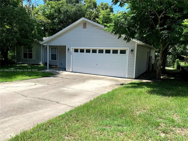a view of a house with a yard and large tree