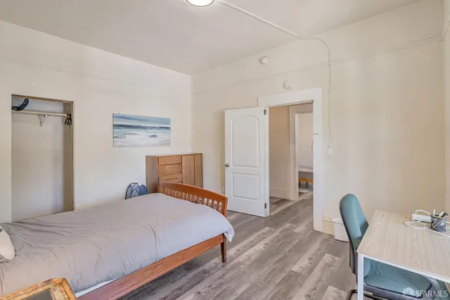 a bedroom with a bed a chair and potted plant on the dresser