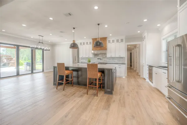 an open kitchen with kitchen island wooden floor and stainless steel appliances