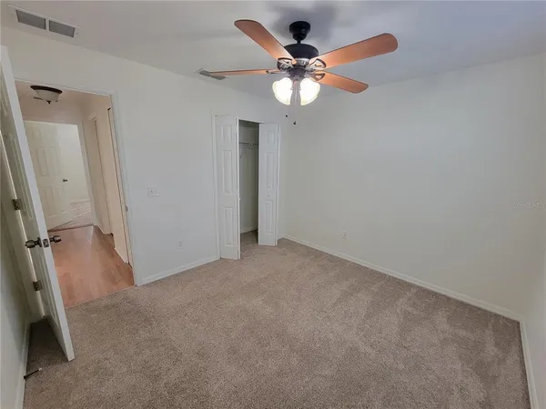 an empty room with a chandelier fan and a bathroom