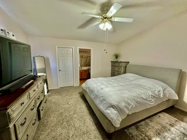 a bedroom with a bed dresser and a flat tv screen