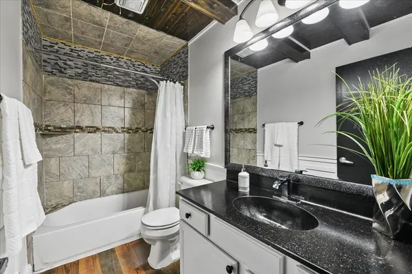 a bathroom with a granite countertop sink a toilet and shower