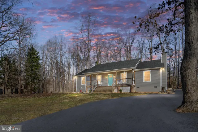 a front view of a house with a garden and tree