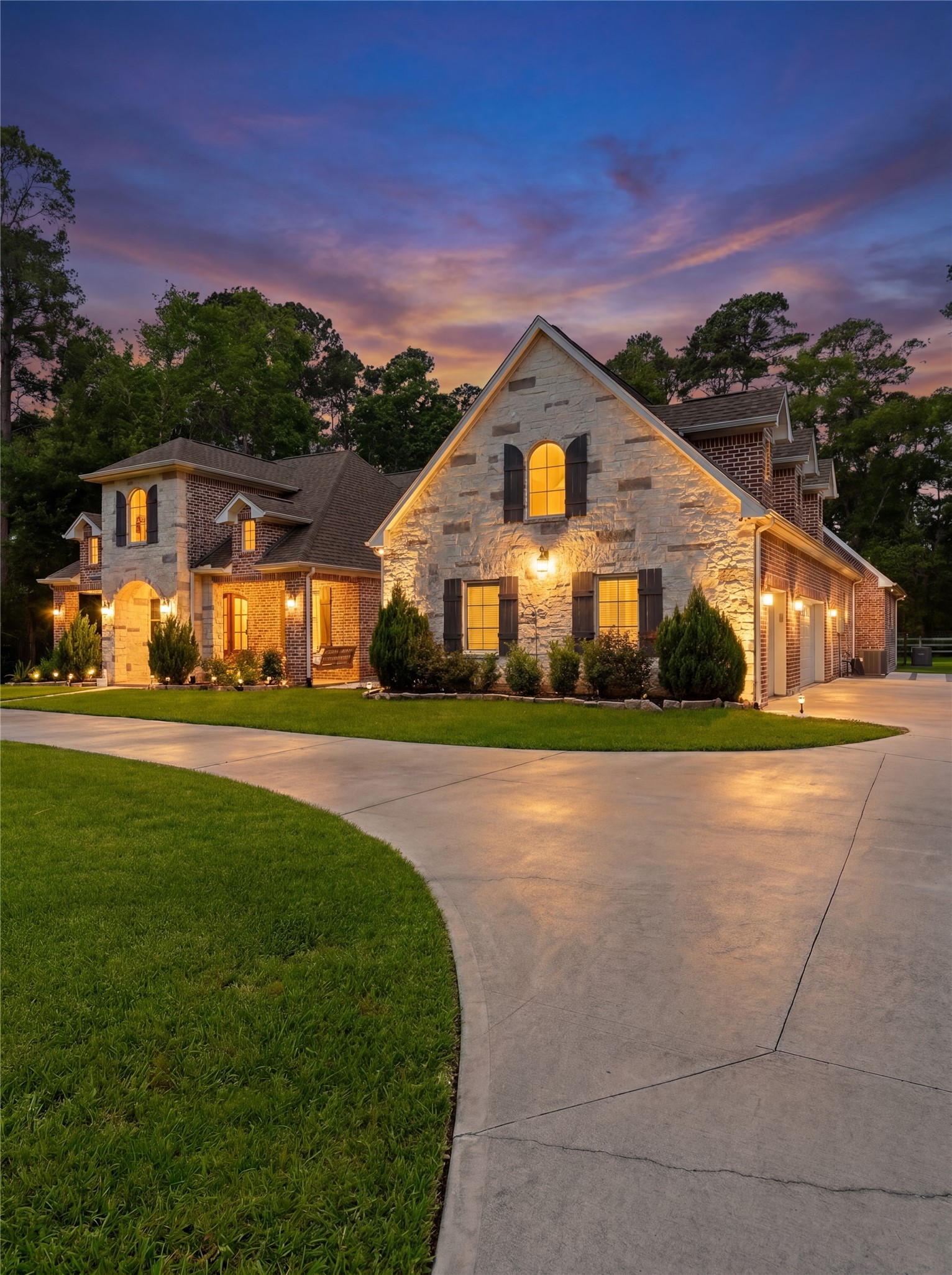 7106 Hampton Court Spring, TX 77389 - Photo 29 of 31 This stunning home features a beautifully lit stone exterior with charming architectural details. The spacious driveway leads to an attached garage, surrounded by well-maintained landscaping.