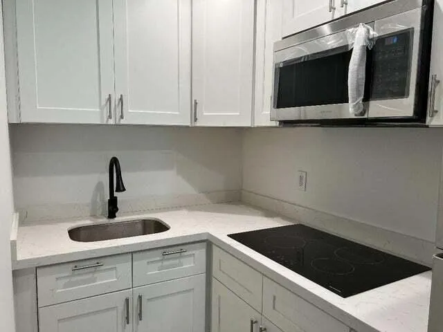 a kitchen with white cabinets and sink