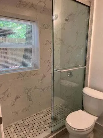 a white toilet sitting next to a shower