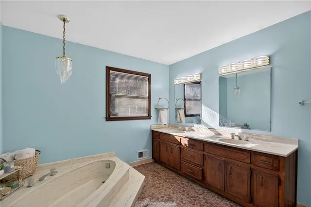 a spacious bathroom with a tub sink and mirror